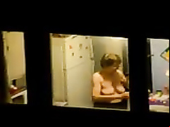 Large-breasted granny changes her clothes by the window
